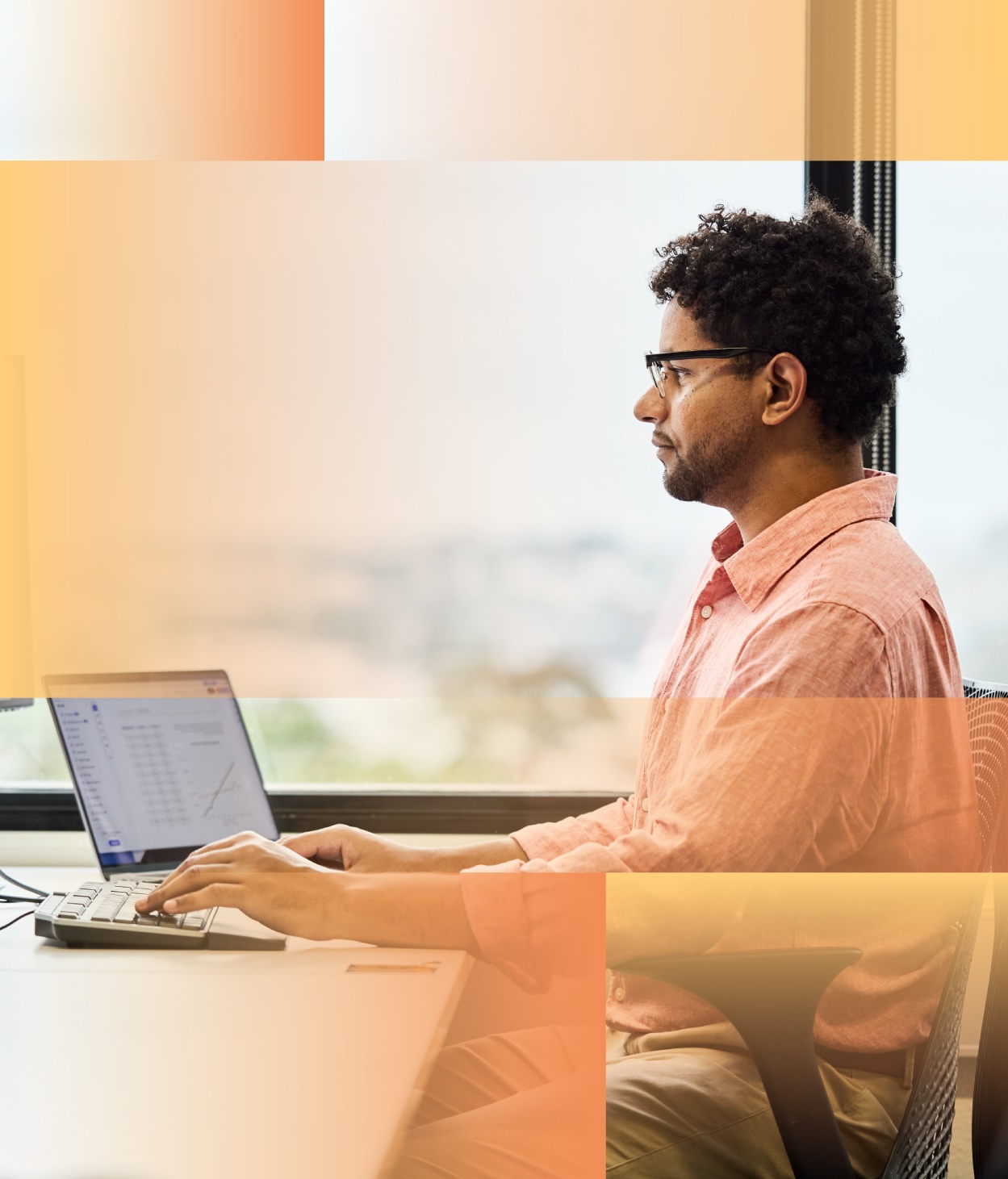 Man with glasses working on a computer at this desk